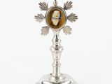 une image représentant une croix en argent sur laquelle figure le portrait d'un homme