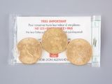 three gold coins in a plastic bag on a white surface