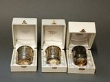 three silver cups in a white box on a gray surface