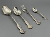 six cuillères et une fourchette en argent sur une surface grise