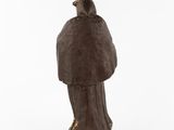 an old statue of a bird sitting on top of a tree stump
