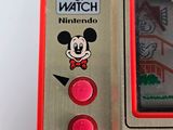 a red and silver game and watch with a mickey mouse sticker on it