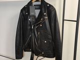 une veste en cuir noir suspendue à un portant dans un magasin de vêtements