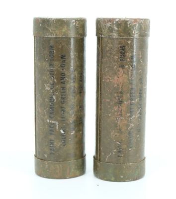 pair of old metal containers sitting on top of a white surface