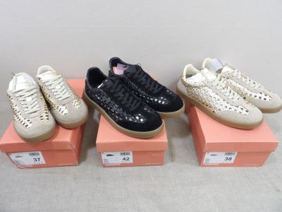 Trois paires de baskets pour femmes sont exposées dans une boîte rose
