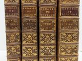 quatre vieux livres posés l'un sur l'autre sur une surface blanche