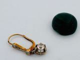 une paire de boucles d'oreilles posées sur une surface blanche