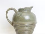 a green vase that is sitting on a white surface