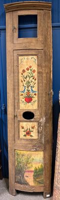 une grande armoire en bois ornée d'un tableau, à côté d'une pile d'autres objets