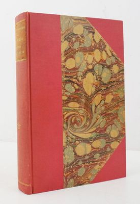 un vieux livre à la couverture rouge posé sur une table blanche