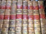several old books are stacked on top of each other on a shelf