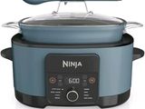 a blue and black crock pot with a spoon in it