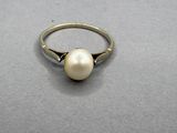 a close up of a ring with a pearl on it