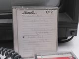 a cassette sitting next to a phone on a desk