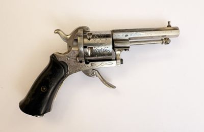 un vieux revolver argenté avec une crosse noire sur un fond blanc