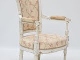 an old white chair with a floral upholstered back and arms