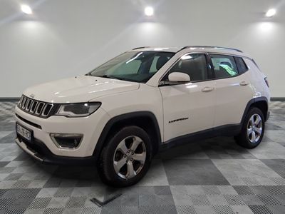 La Jeep Compass blanche est garée sur un sol en carrelage à damier.