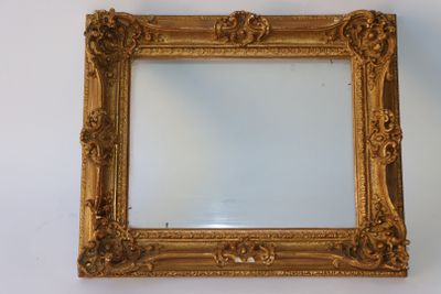 un cadre doré ancien avec un miroir accroché à un mur blanc