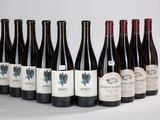 six bouteilles de vin sont alignées sur une surface blanche