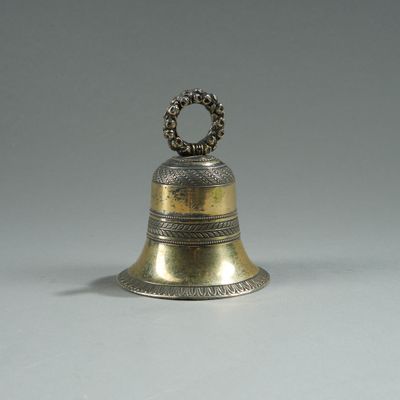 brass bell with a ring on top of it on a white surface