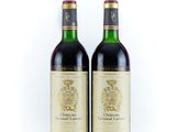 two bottles of wine sitting next to each other on a white surface