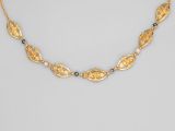 a gold necklace with blue stones and gold leaves
