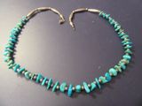 un gros plan d'un collier orné de perles de turquoise posé sur une table