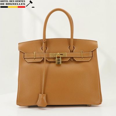 un sac à main en cuir marron muni d'un fermoir doré sur la poignée