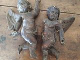paire d'ustensiles anciens en fonte représentant des anges, posés sur une table en bois