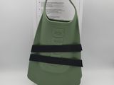 a green bag with a black strap on it sitting on top of a white table