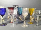 several different colored glass goblets are lined up on a gray surface