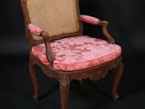 une vieille chaise en bois dont l'assise est recouverte de tissu rose