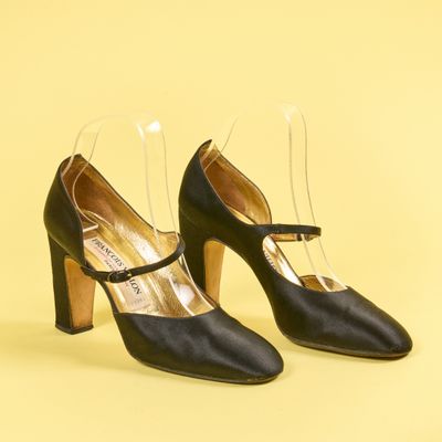 une paire de chaussures noires à talons transparents sur fond jaune