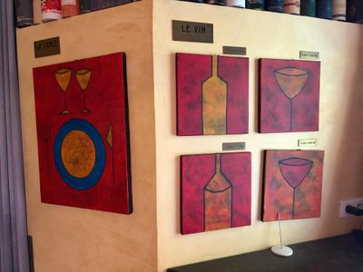 four paintings on the wall of a wine shop
