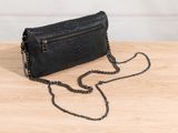 a black snake skin clutch bag on a wooden table