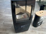 un poêle noir posé sur un sol carrelé, à côté d'une poubelle