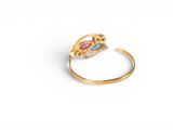 a close up of a gold ring with a pink and blue stone