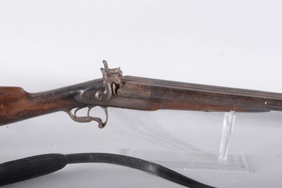 un vieux fusil avec un canon en bois et une sangle noire