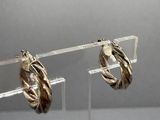 pair of silver and gold hoop earrings on clear acrylic stand