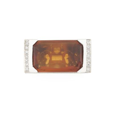 un gros plan d'une bague sertie d'une pierre orange et de diamants