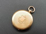 an image of a gold pocket watch on a black surface