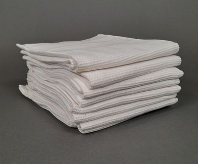 des serviettes blanches empilées les unes sur les autres sur une surface grise