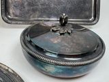 a silver box with a lid on a table next to other silver items