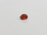 an orange sapphire stone on a white surface