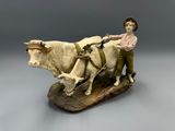 figurine of a boy on a plow with two cows