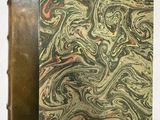 un vieux livre orné d'un motif marbré, posé sur une table