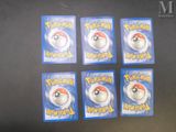 six pokemon trading cards sitting on top of a black table