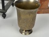 a silver cup sitting on a table next to a chair