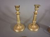 pair of antique brass candlesticks on a table next to a coin