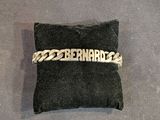 un bracelet à chaîne en argent avec un prénom gravé, posé sur un coussin noir